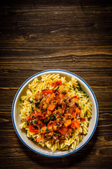 Pasta with tomato sauce and vegtables on wooden table 