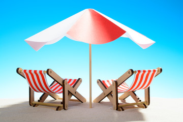 Two chaise longue under an umbrella on the sandy beach, sky with copy space