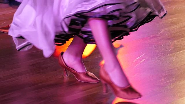 Legs of girls of dancers on a parquet floor, slow motion.