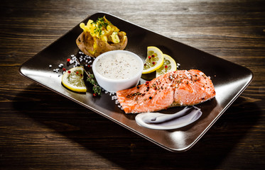 Roast salmon with potatoes on wooden table