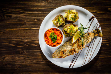 Fish dish - roast trout with almonds and vegetables on wooden table