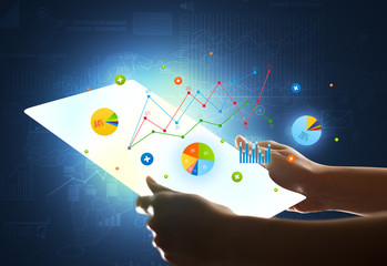 Hands touching a glass-like tablet with charts