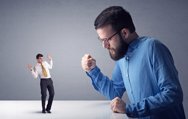 Young businessman fighting with miniature businessman