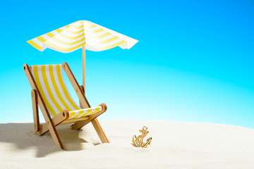 A chaise longue under an umbrella on the sandy beach, sky with copy space