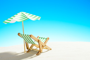 A chaise longue under an umbrella on the sandy beach, sky with copy space