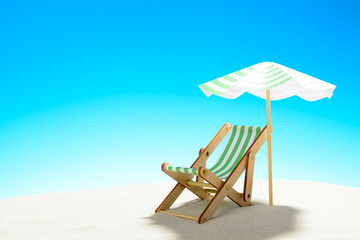 A chaise longue under an umbrella on the sandy beach, sky with copy space