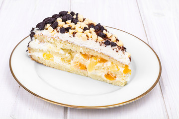 Delicious piece of cake with fruit, whipped cream and chocolate drops