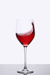 red wine swirling in a wine glass standing against light background