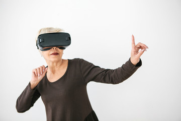 An elderly woman in virtual reality glasses. An elderly person using modern technology.