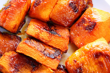 Pumpkin, ultraviolet background, baked pumpkin with honey, white plate with orange vegetables, pop art, slices of pumpkin on purple background, vegetarianism, healthy food, macrophotography