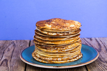 Stack of hot delicious pancakes on bright violet background
