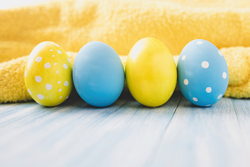 Blue and yellow Easter eggs on rustic background