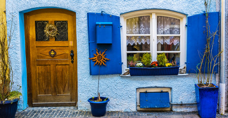 Fototapeta na wymiar Beautiful facade of the house with wooden door, shutters and flowerpot for plants, Fussen, Germany