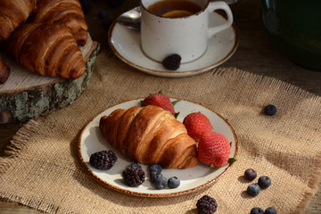 The freshly baked croissants for breakfast with berries and green tea 