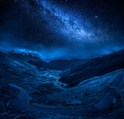 Winding mountain road over a canyon at night with stars