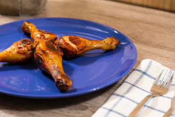 four chicken drumsticks marinated in hot sauce on a blue plate and wooden table