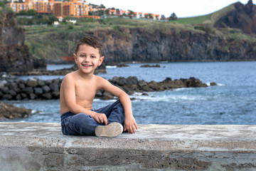 Naklejka na ściany i meble little boy sitting on the beach