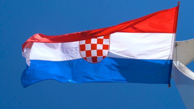 Croatia flag waving in the wind against blue sky in summer in harbor of Split old town in Croatia.