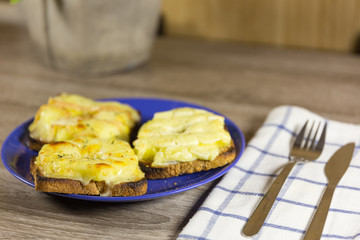 three pineapple toasts with golden melted cheese on top on blue plate