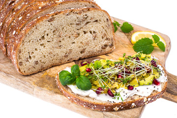 Whole grain bread with avocado, green sprouts and pomegranate seeds