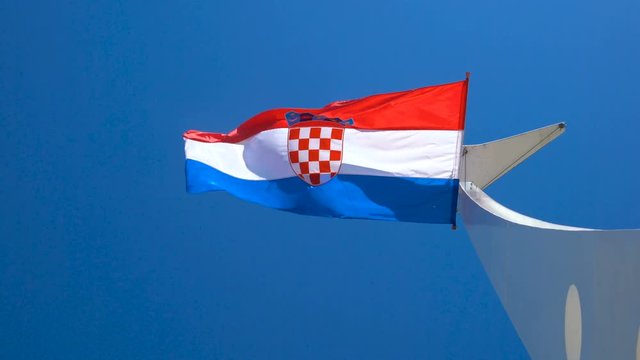 Croatia flag waving in the wind against blue sky in summer in harbor of Split old town in Croatia.