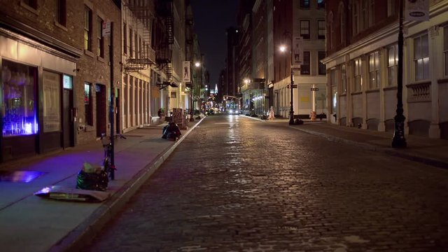 desolate empty sidewalk at night - deserted cobblestone street with blinking neon lights in SoHo Manhattan New York City NYC in 1080 HD