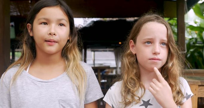 Two shy awkward young girls standing next to each other waiting