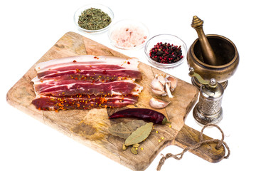 Slices of smoked bacon with light on wooden kitchen cutting board