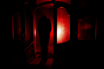 Silhouette of an unknown shadow figure on a door through a closed glass door. The silhouette of a human in front of a window at night. Scary scene halloween concept of blurred silhouette