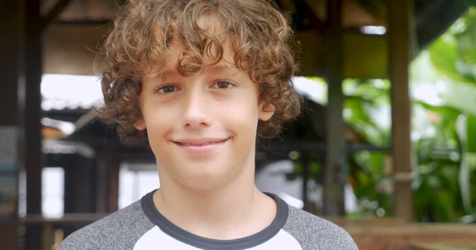 Portrait of a cute young 11 - 12 year old boy with curly hair smiling