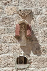 Hvar, Croatia. Crucifix and old pictures of Virgin Mary carved into stone building wall.
