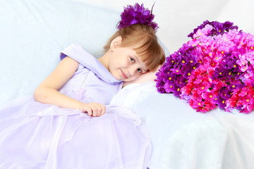 Girl sits next to a bouquet of flowers.