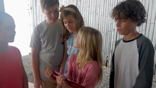 Group of young friends looking at a digital tablet together smiling and talking