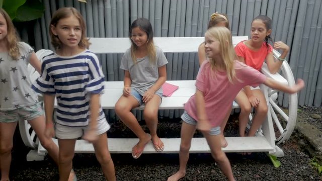 Diverse group of young girls getting off a bench to join their friend dancing