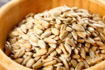 Black peeled sunflower seeds in a wooden bowl on a wooden table.