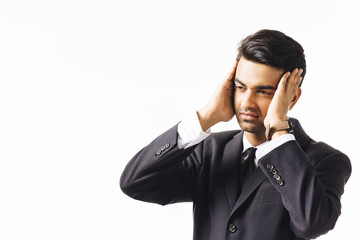 Portrait of a worried man in business suit and tie holding his head with both hands, isolated on white studio background