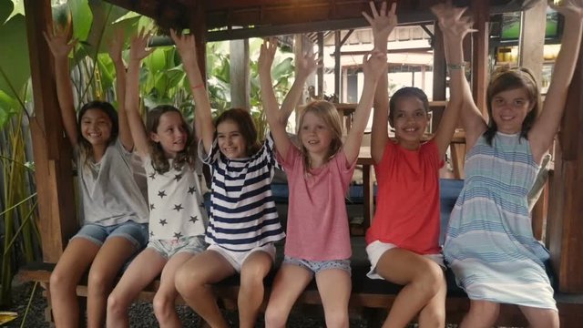 Happy group of young girls waiving their arms in the air sitting together