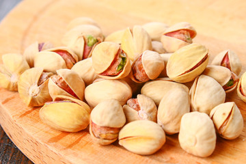 Dish full of pistachios with more pistachios on side.