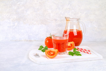 Tomato juice in glasses and a pitcher on a gray concrete table.