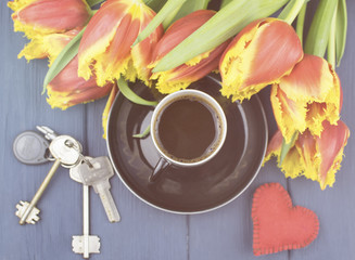 cup of coffee, house keys with red felt heart on a blue wooden surface