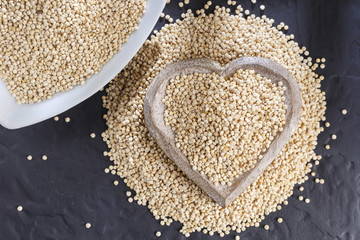 Quinoa grains with spoon and bowl on black background