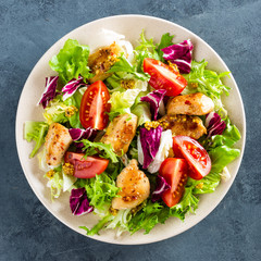 Fresh vegetable salad of tomatoes, cucumbers, italian mix, lettuce and grilled chicken breast. Fried chicken meat, fillet with salad. Healthy food. Flat lay. Top view