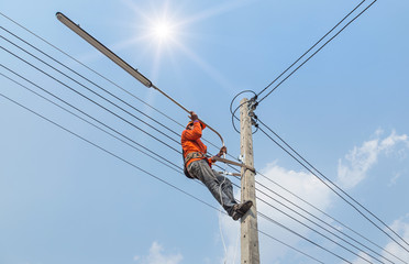 Electrician climb work installing new street lamp
lighting post base electricity. 
