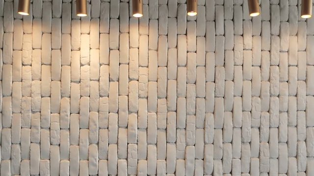 The white brick wall is hilighted with lanterns from above. Texture for background. Empty cement plane. Soft light from lamps is reflected from the wall. Retro loft space in a hipster style.