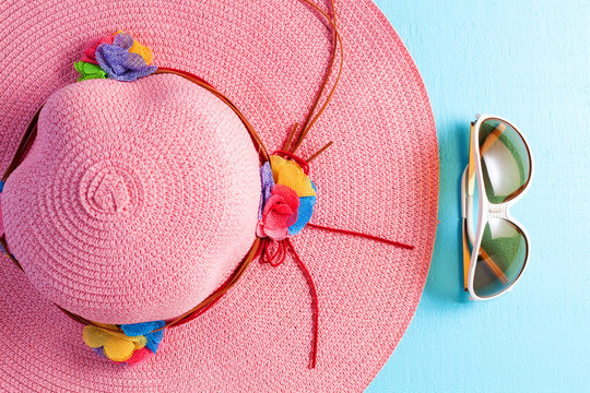 Beautiful lady beach hat with sunglasses on blue wooden background,summer holiday background concept.
