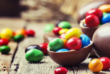 Easter composition with chocolate eggs and colorful candy, vintage wooden background, selective...