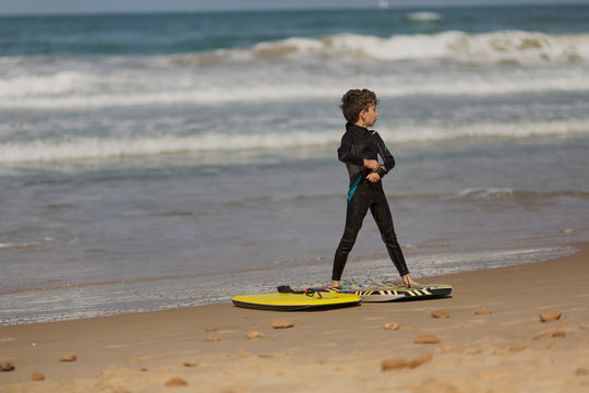 young surfer with bodyboard has a fun on sea sand beach. Active family lifestyle, people outdoor water sport lessons and swimming activity on surf camp summer vacation with child.