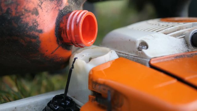Close up of chainsaw being refulled, hand closes cap to seal
