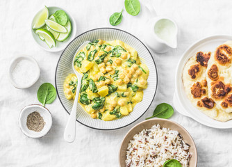 Vegetarian chickpea, spinach, potato curry, naan flatbread and wild rice on white background, top view. Indian healthy food concept