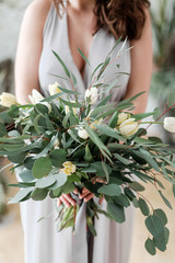 Lush bouquet of eucalyptus and tulips in the hands of the bride